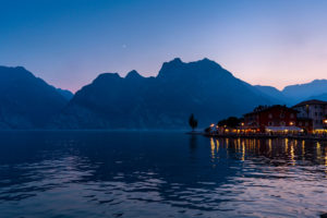 Moonrise over the waterfront restaurants and hotels of Torbole in the north of Lake Garda, Italy